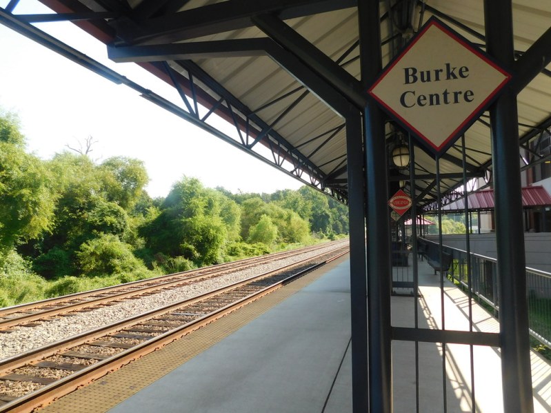 Image of Burke Center Train Station, with tracks and greenery to the left of the platform